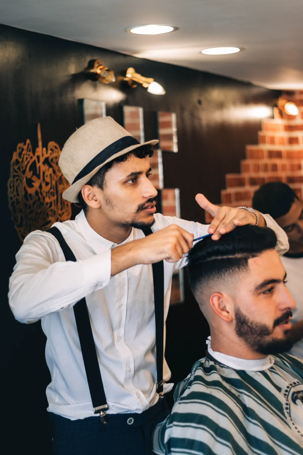 Barbeiro de chapéu e suspensórios cortando o cabelo de um cliente