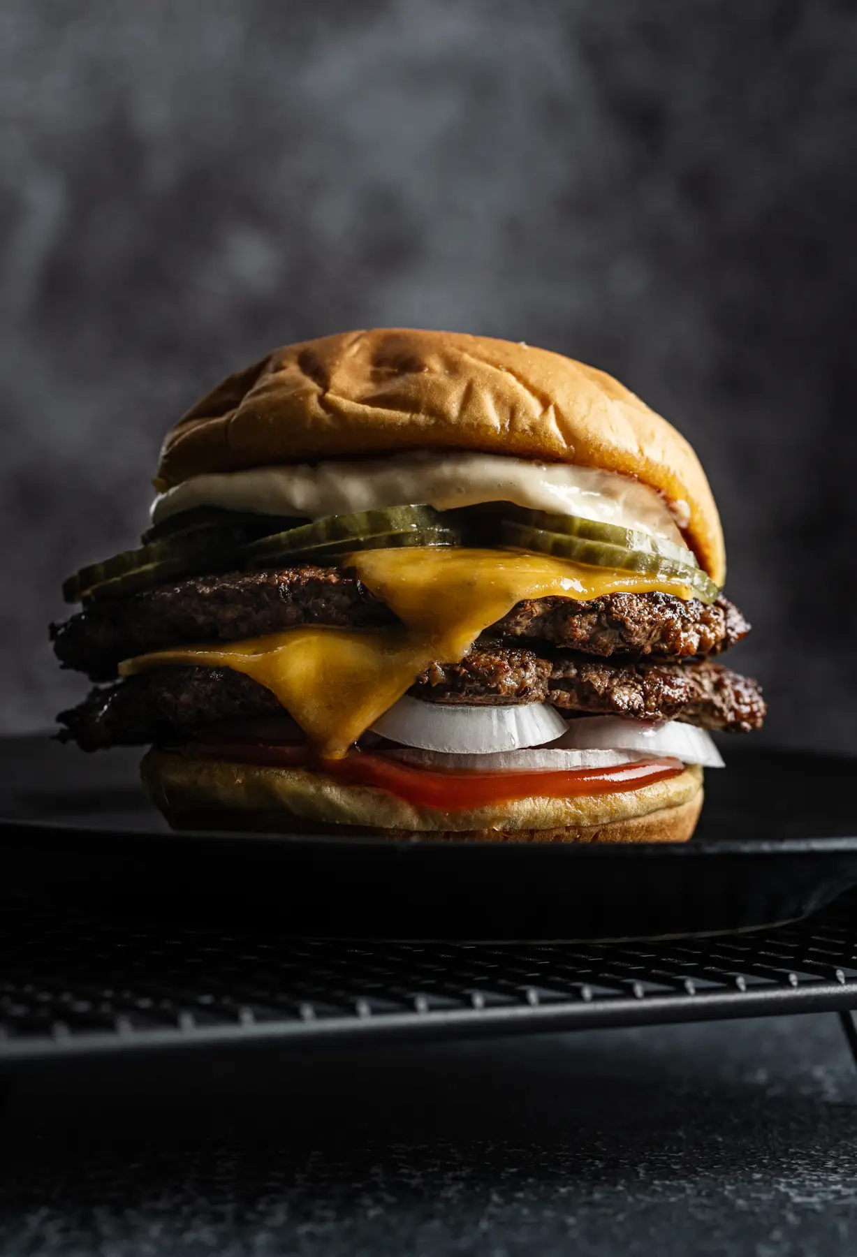 Hambúrguer clássico com cheddar derretido e picles sobre fundo escuro