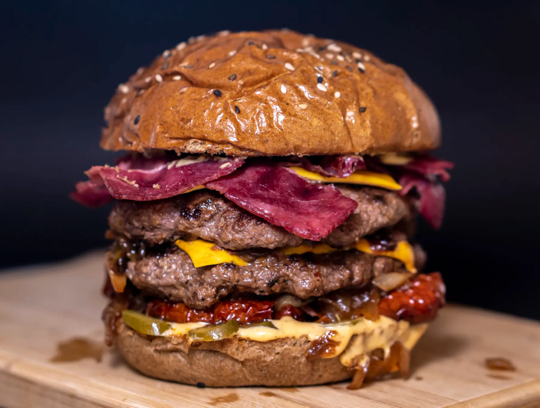 Hambúrguer triplo alto com pastrami e queijo sobre tábua