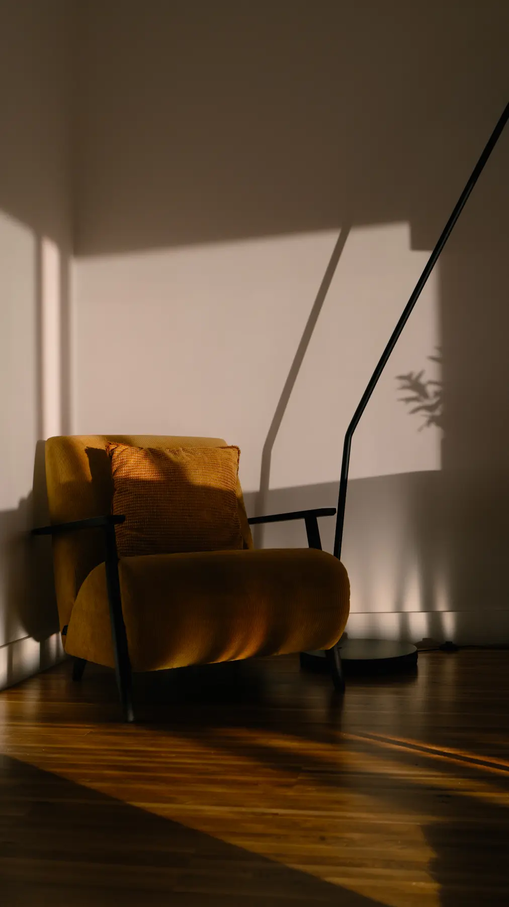 Poltrona amarela iluminada por uma faixa de sol da tarde, em uma sala silenciosa